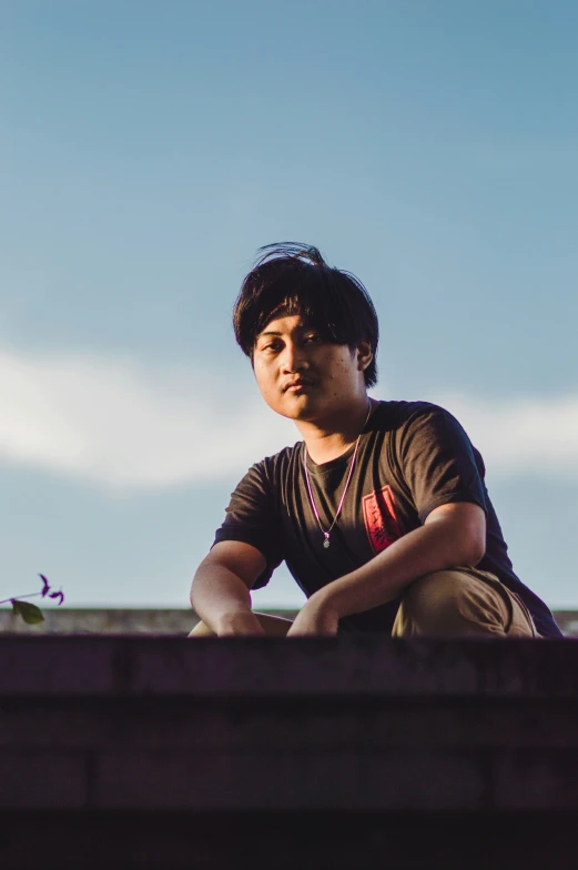 a man sitting down on a wall staring at the camera