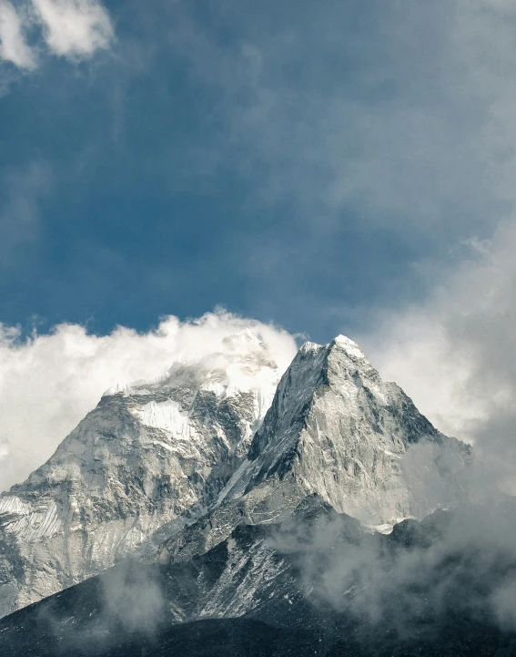 a large snowy mountain with fluffy clouds around it