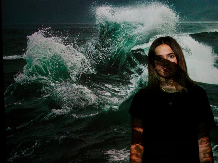 a young man standing in front of a picture of an ocean