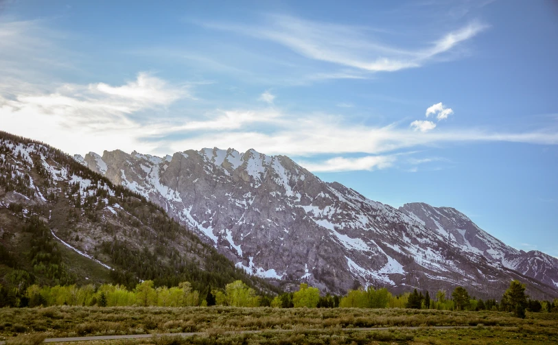 the mountains are covered in snow and surrounded by grass