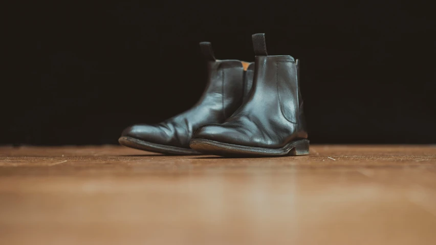 a pair of black boots sitting on top of a wooden floor