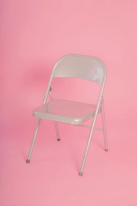 a folding chair against a bright pink backdrop