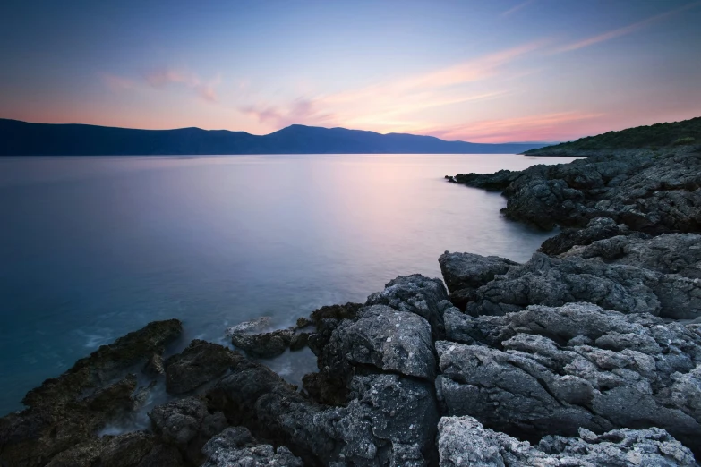 some water rocks and a mountain at sunset