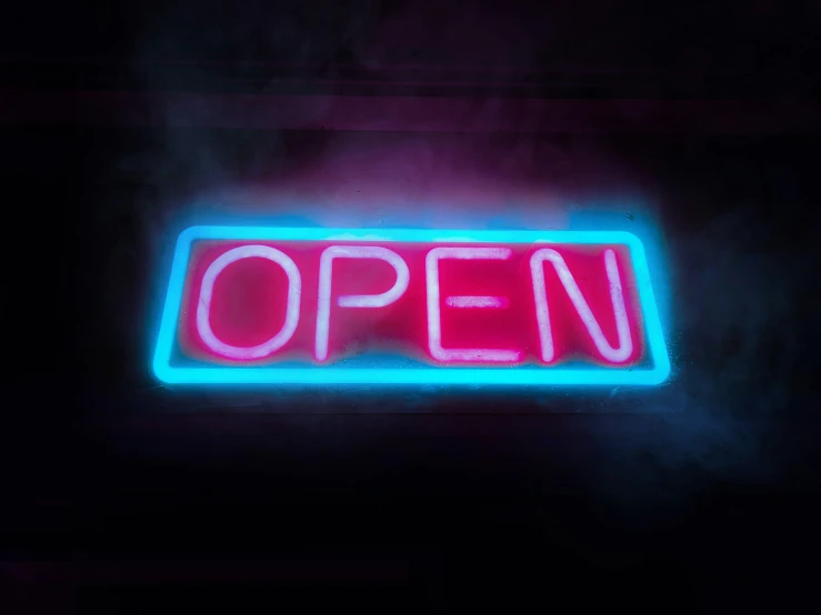 a neon sign that reads open is in the dark