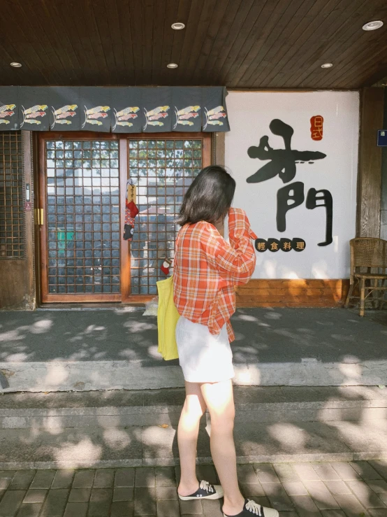 a woman in plaid shirt looking at oriental sign