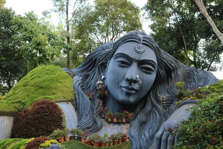 a statue sitting in the middle of lush green plants