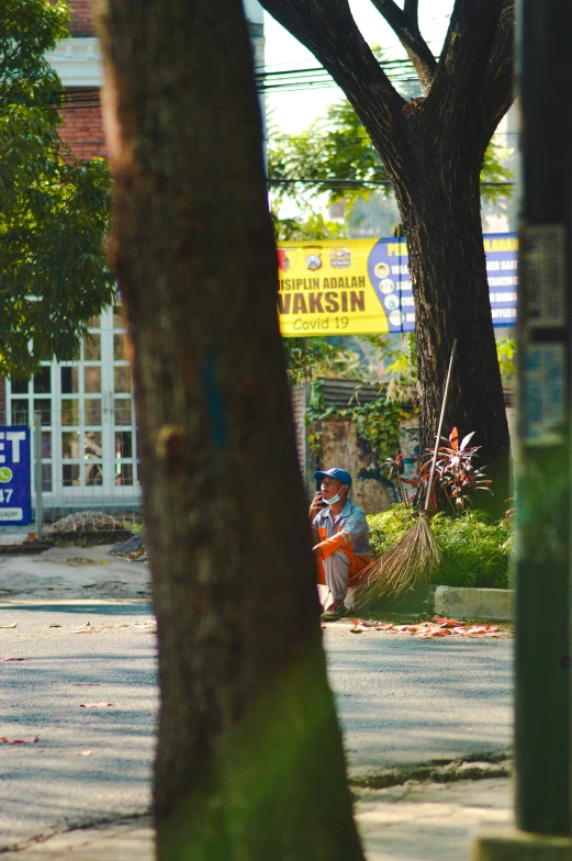 two people are sitting on the sidewalk next to a tree