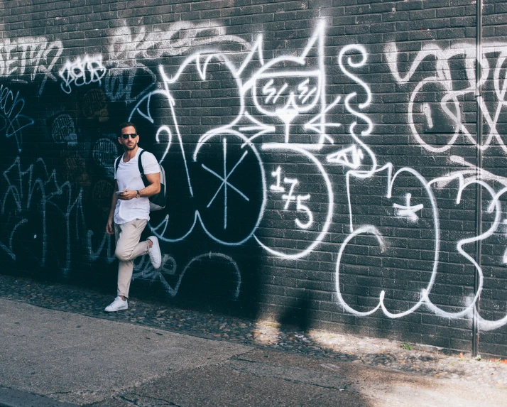 a man standing next to a graffiti covered wall