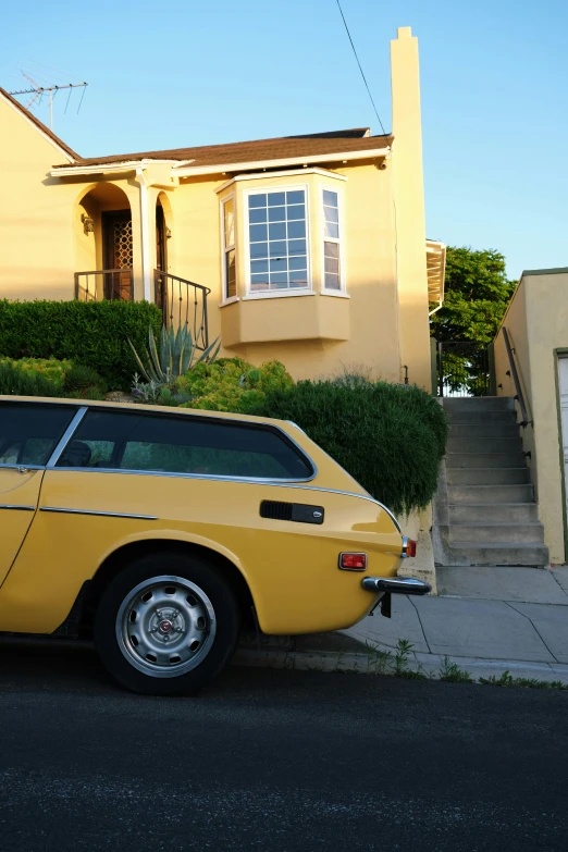 a yellow car sits in front of a large house