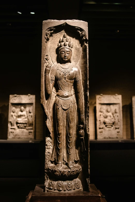 a carved statue in a dark room next to other statues