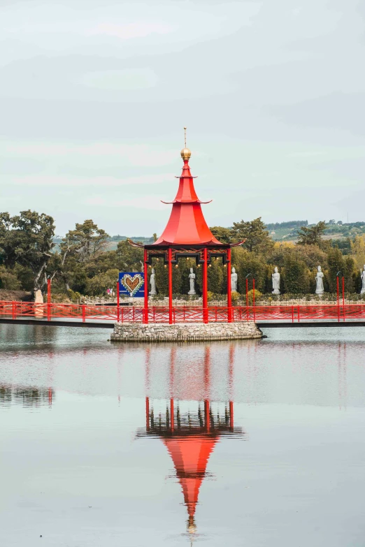 an orange gazebo and pavilion sits in a lake