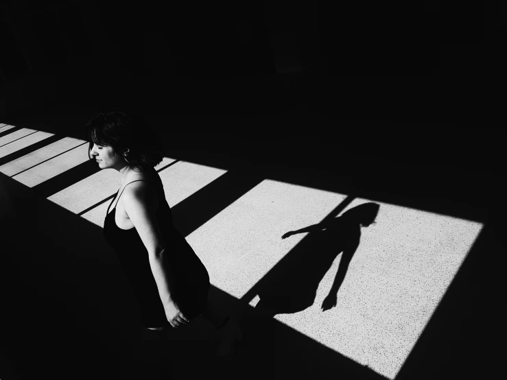 the woman is wearing black swimsuit and shadow on concrete floor