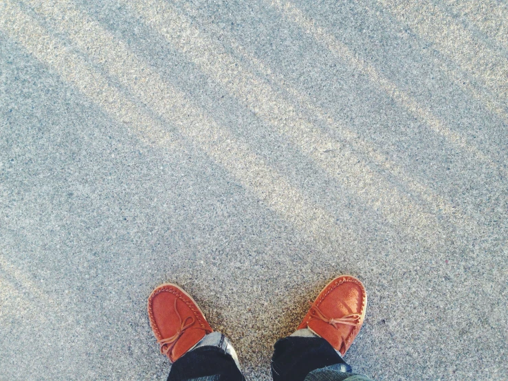 an orange shoe with red shoes is standing on a sandy area