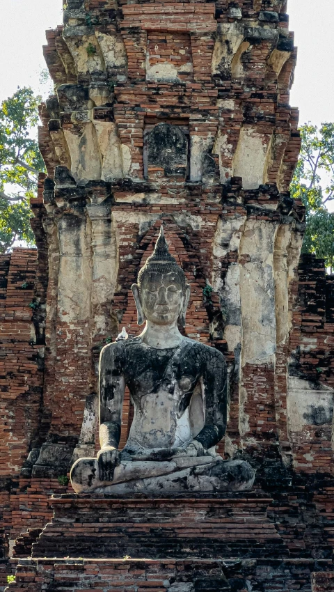 a buddha statue is sitting in front of a stone gate