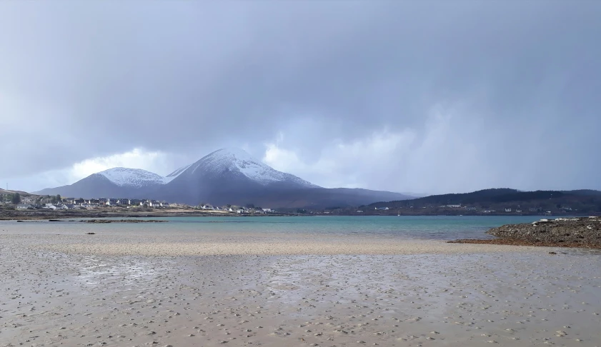 a large beach with a snowy mountain in the distance