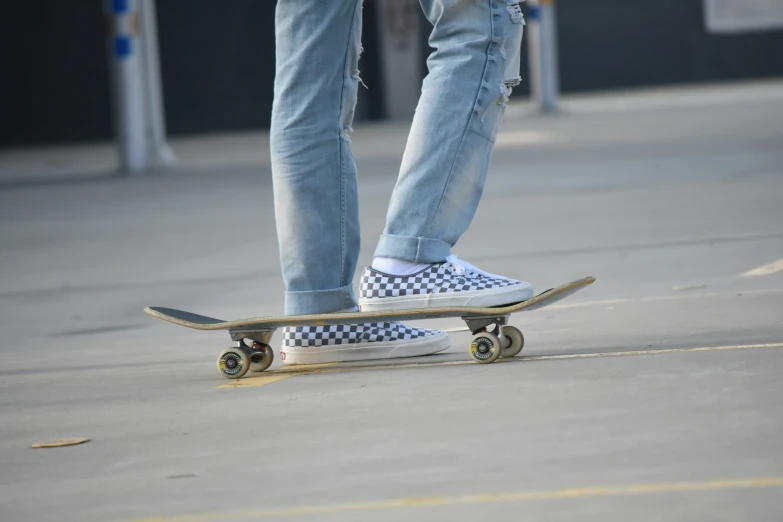 the person wearing sneakers and jeans stands with their skateboard