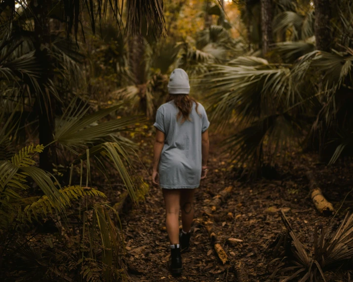 a person with long hair walking in the woods