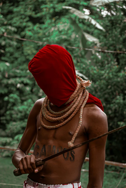 a person in a red head dress holding a stick