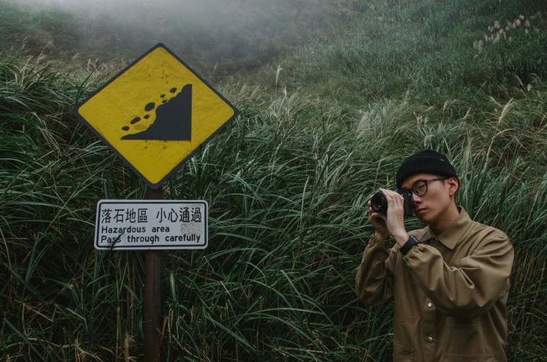 a man taking a picture next to a sign on a foggy day