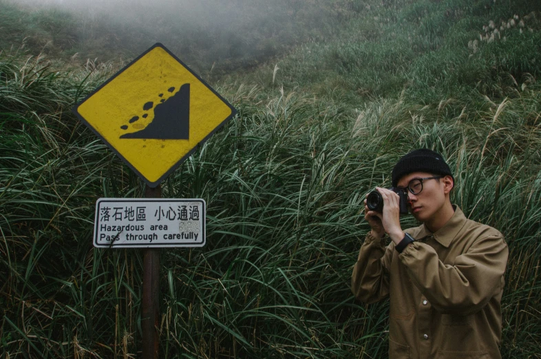 a man taking a picture next to a sign on a foggy day