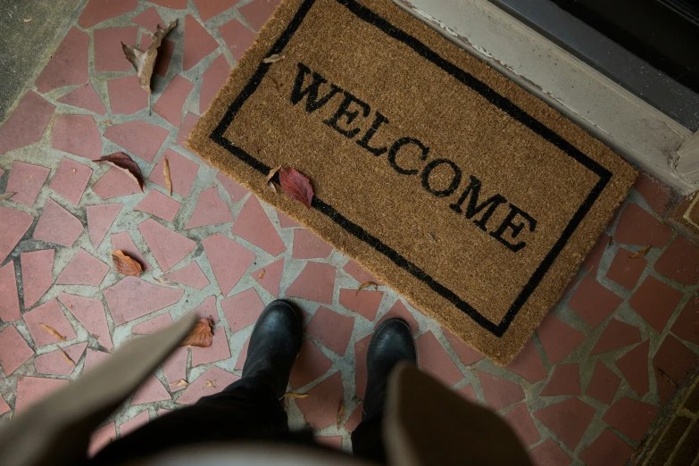 there is a welcome mat between two people standing near a door