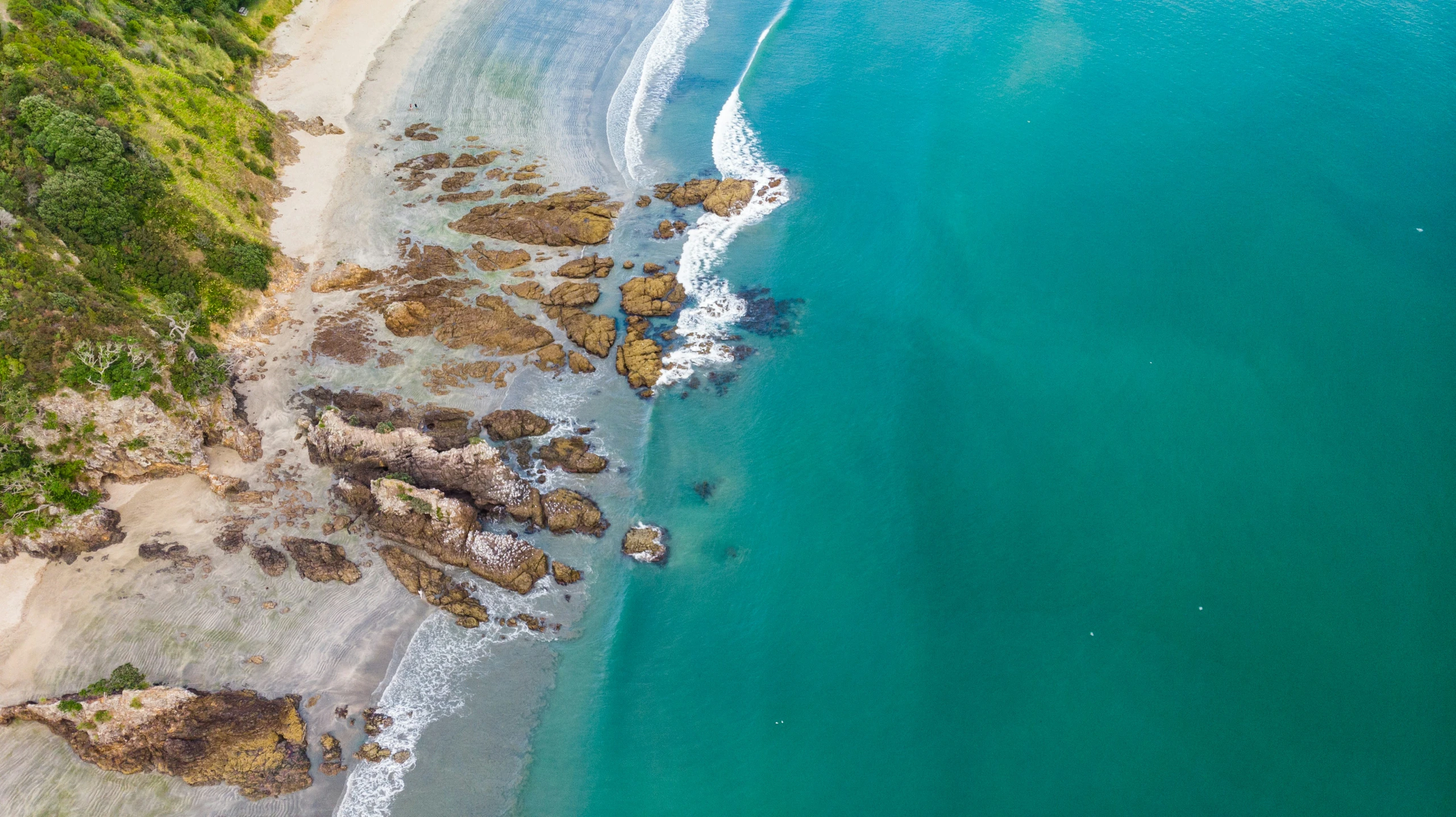 an aerial po of a beach with rocky coastline