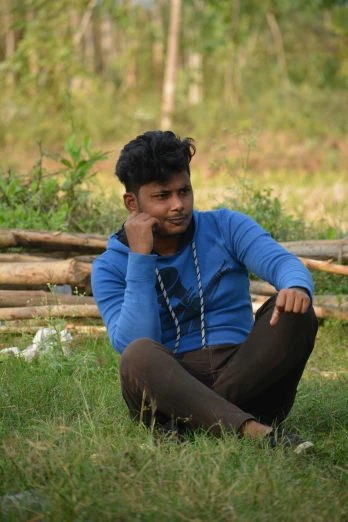 a man sitting in a grass area and looking at the camera
