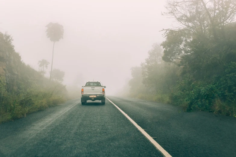 a truck driving on the side of a road in fog