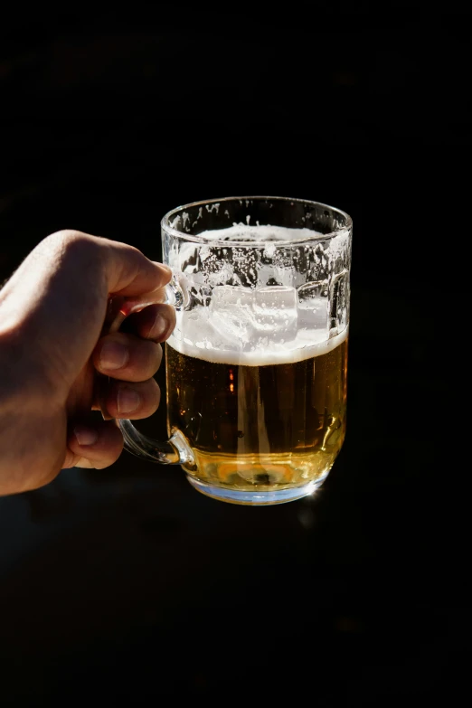 someone holding onto a glass of beer on the table