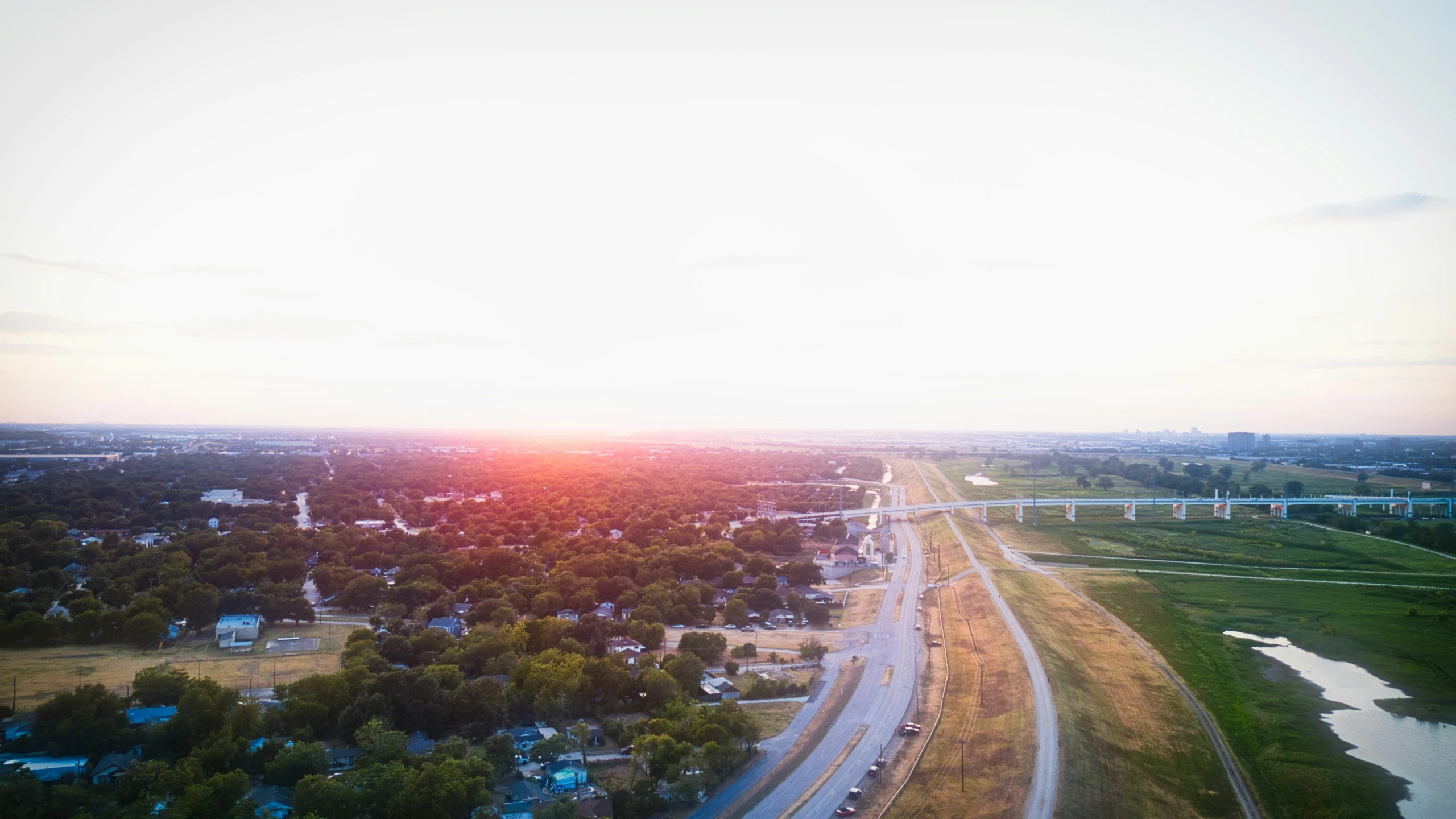 this aerial view shows an area with green fields and large trees that can be seen from above, the sun is setting behind