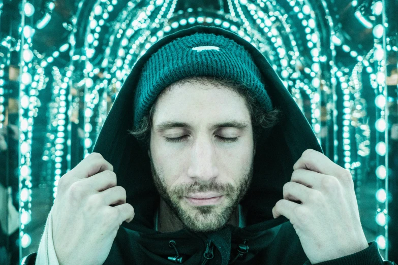 a man with a hoodie over his head in front of a wall of lights