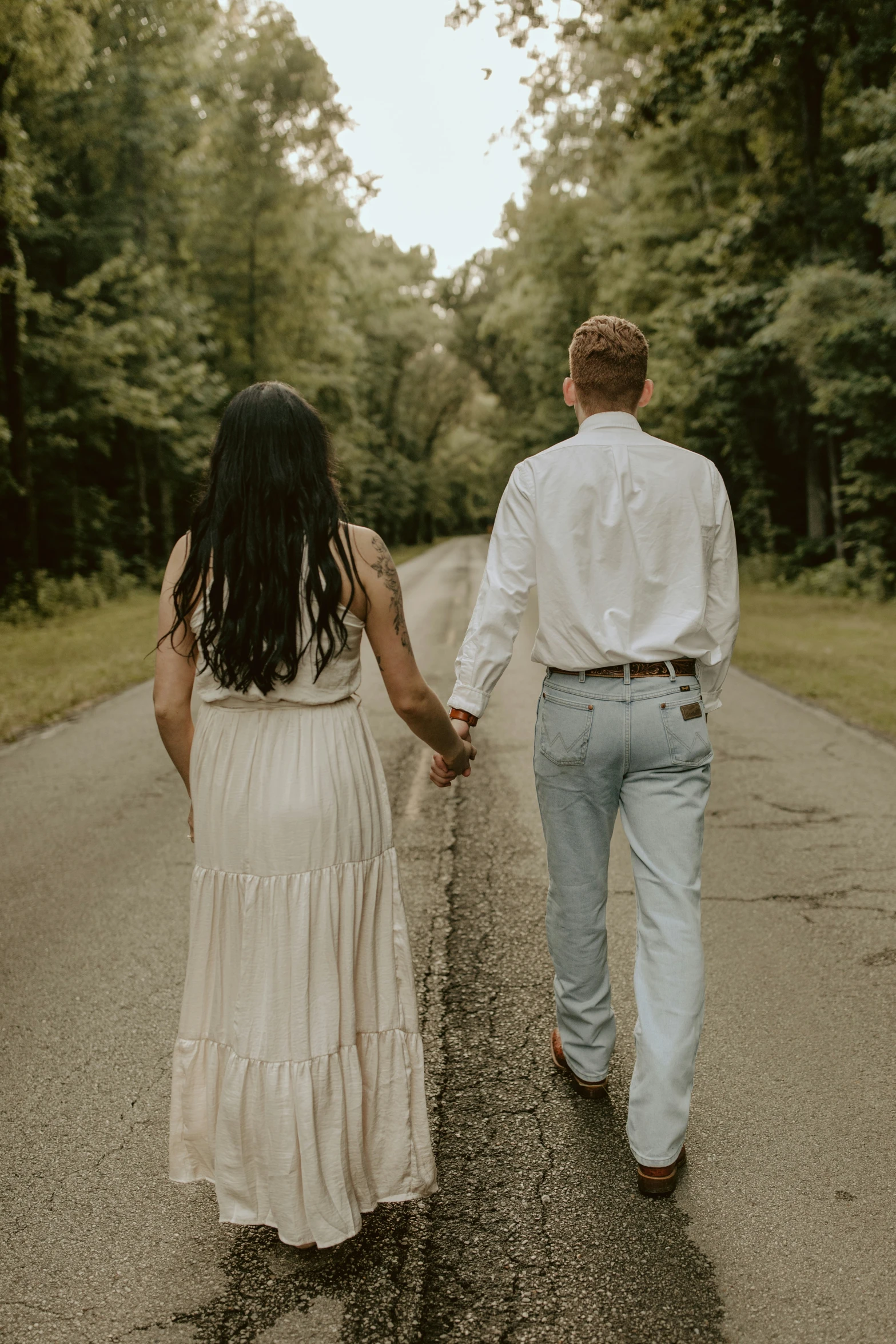 a man and a woman holding hands as they walk down the road