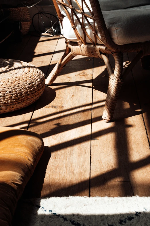 a rattan covered chair sitting on the floor next to a woven pillow