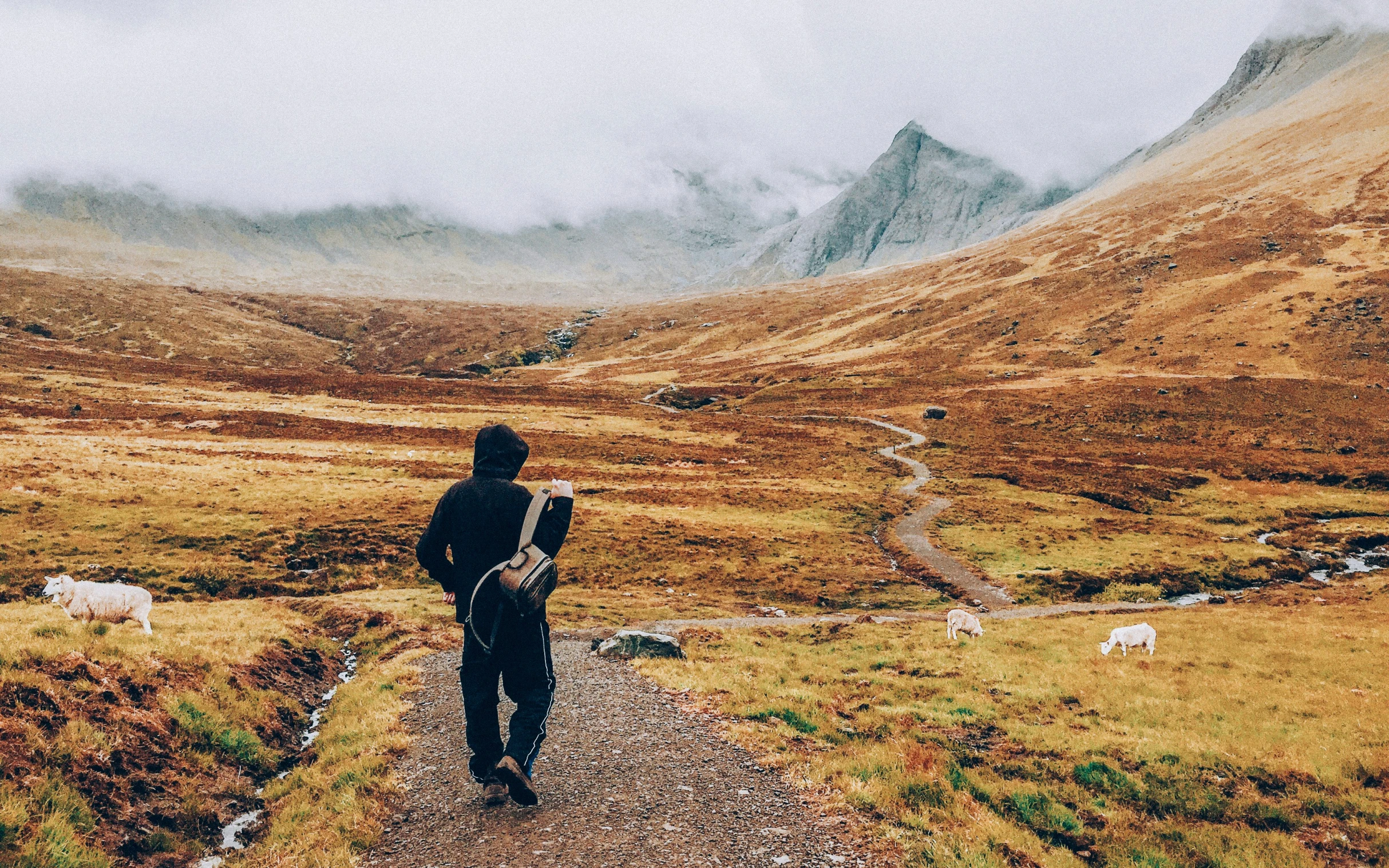 a man standing on a path with mountains and clouds in the background