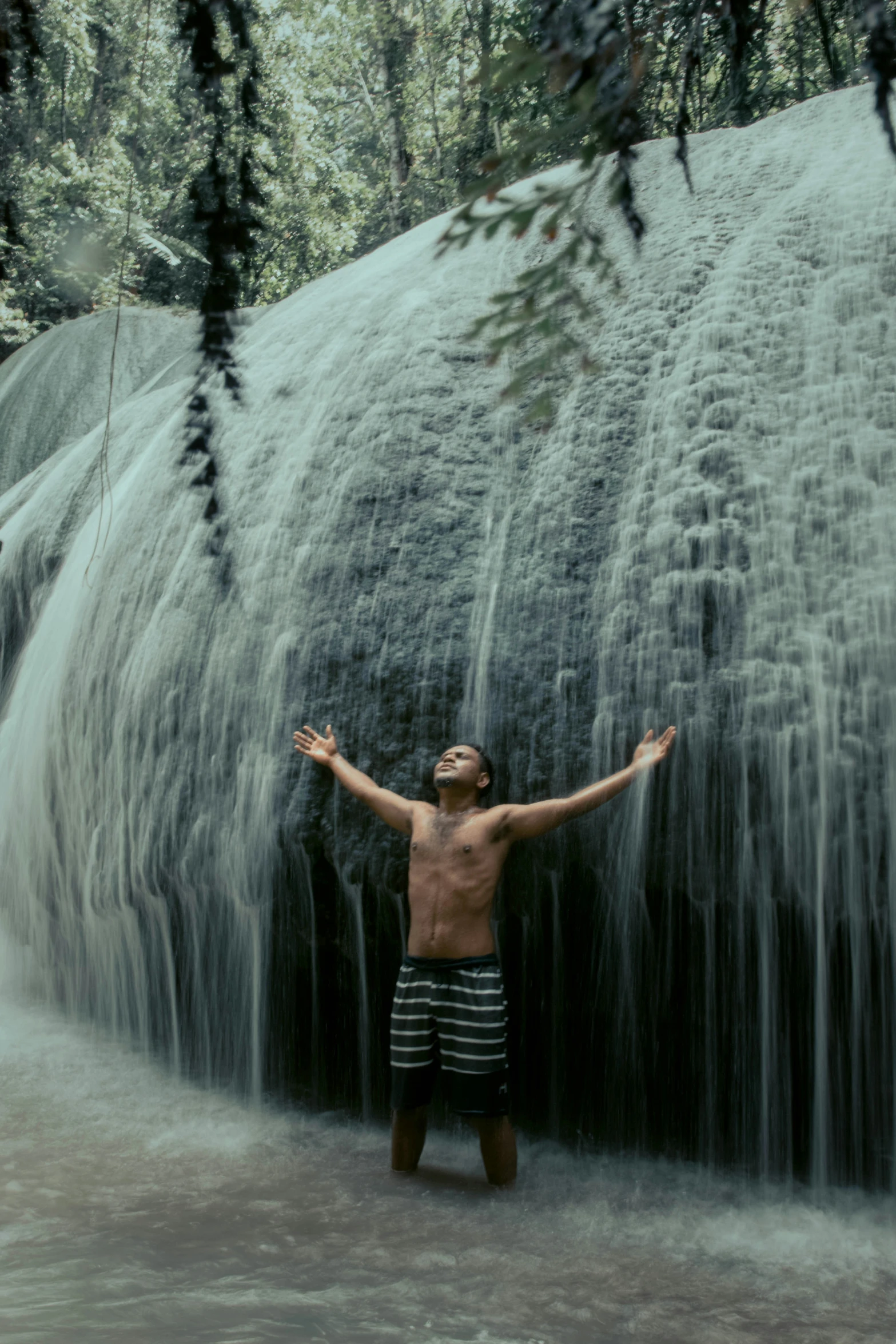 there is a man standing in front of a waterfall