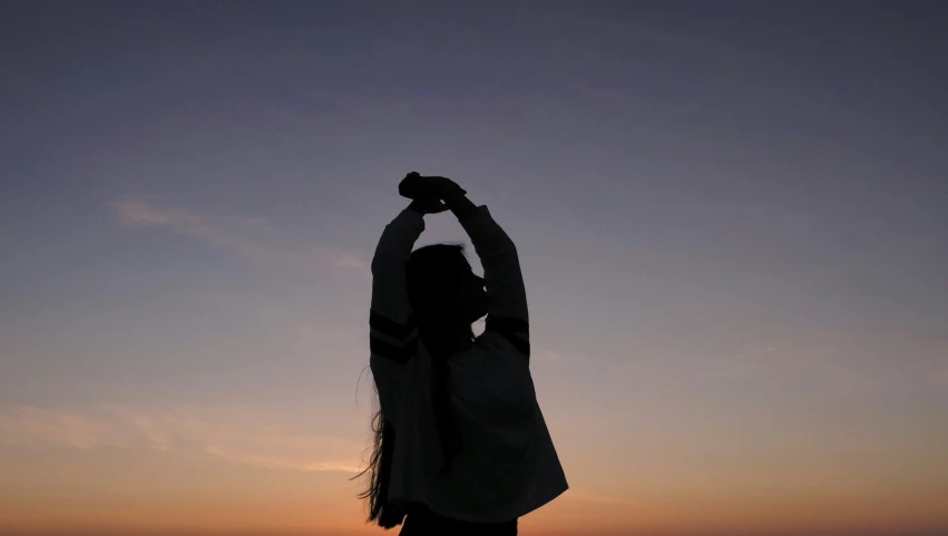 a silhouette of a person holding up their arms