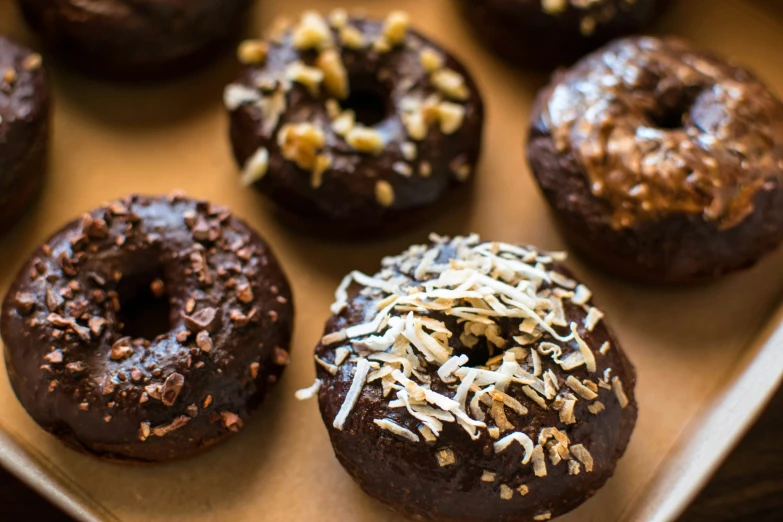 six chocolate donuts covered in nutty toppings and sprinkles