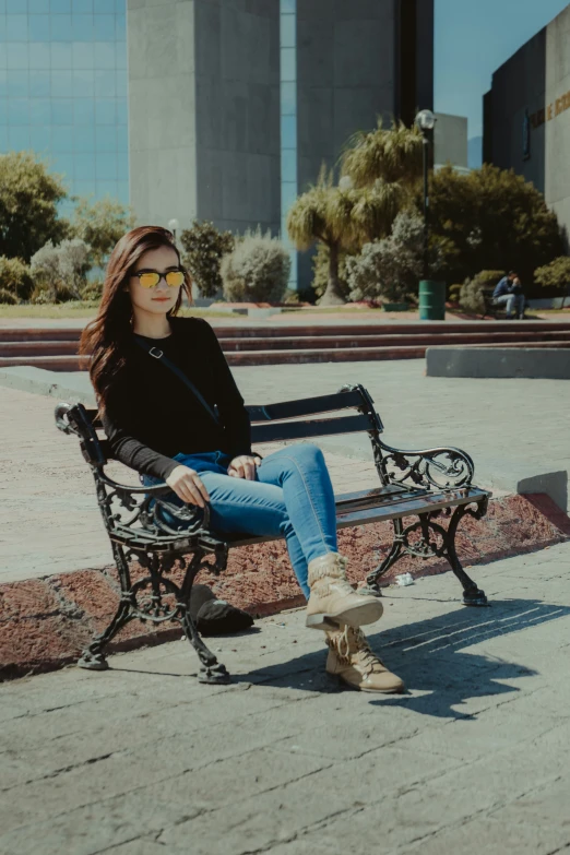 a girl with sun glasses sitting on the park bench