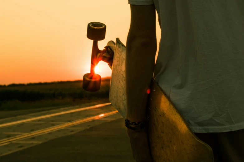 a skateboarder holding his board at the end of a highway