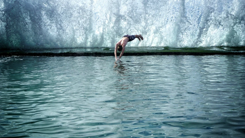 a man in water jumping into a large pool