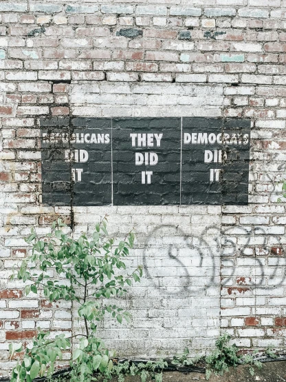 two signs with some graffiti on them on a brick wall