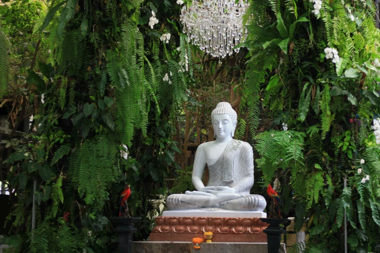 a buddha statue sitting in a garden with trees