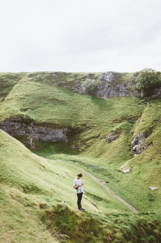 a person standing on a green mountain with grass