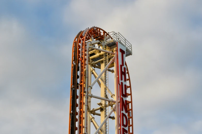 a ride tower with the sky and clouds in the background