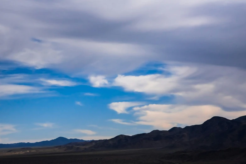 some clouds and mountains and a jet in the air