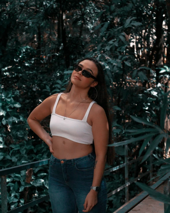 a woman standing in front of trees wearing dark glasses