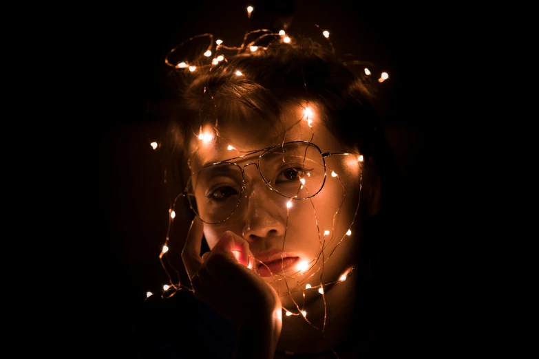 a person wearing glasses is surrounded by small lights