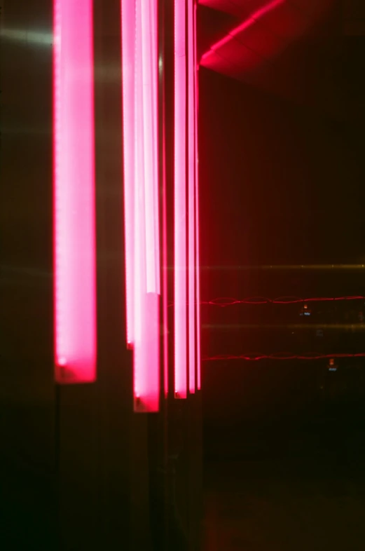 an indoor space with neon pink lights and lighting poles