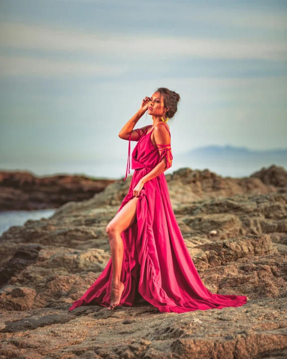 a woman in a red dress posing on some rocks