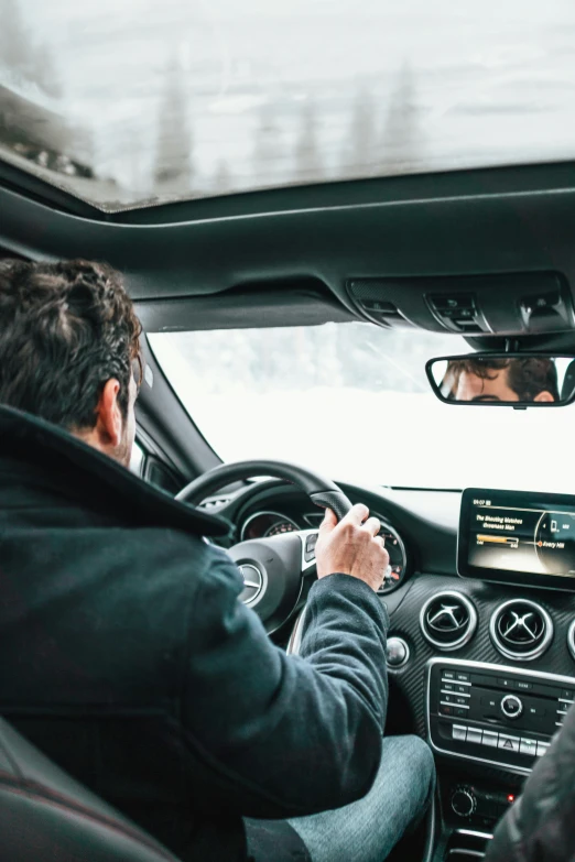 two people sitting in a car, one is holding a cell phone